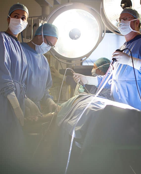 Four surgeons operating over a table with a bright light